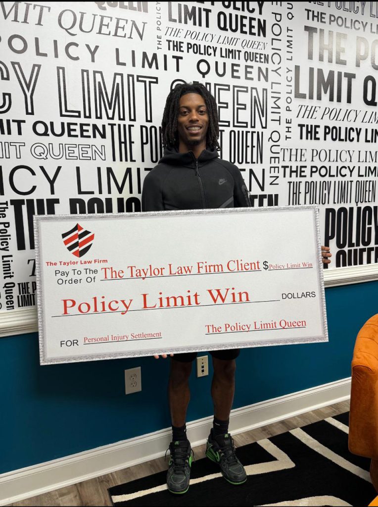Taylor Law Firm client holding a Policy Limit Win check